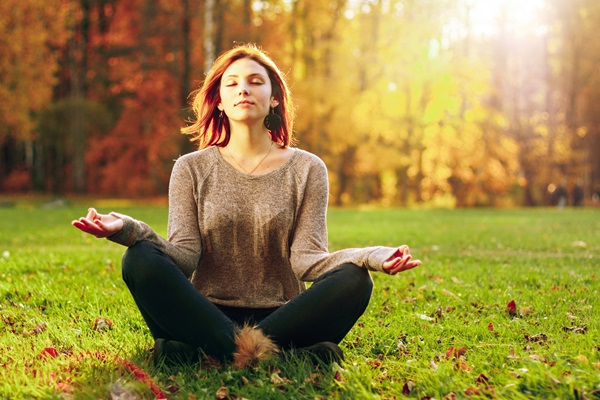 Young attractive female meditate in park.